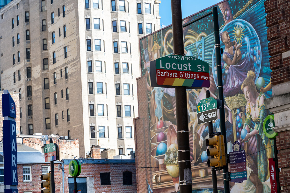 A Philadelphia road sign, decorated in rainbow colors, honors Barbara Gittings, an LGBTQ+ activist.